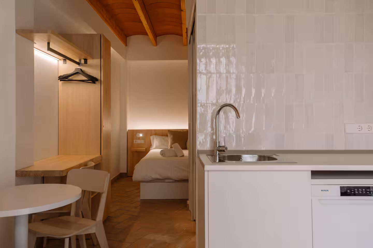 Vista del dormitorio desde la cocina, con perchero de madera y azulejo artesanal