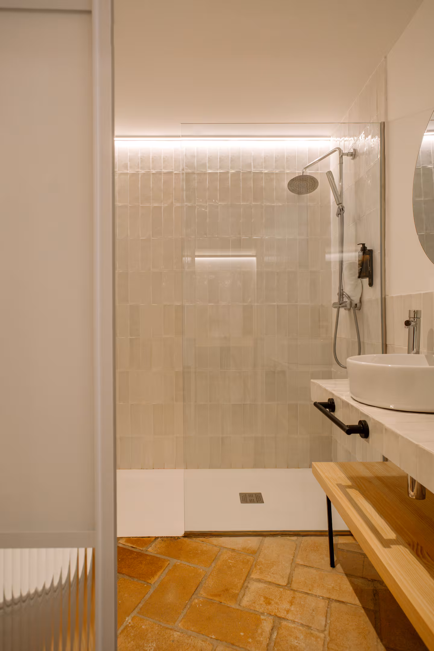 Ducha con mampara de vidrio y suelo de barro cocido en el baño