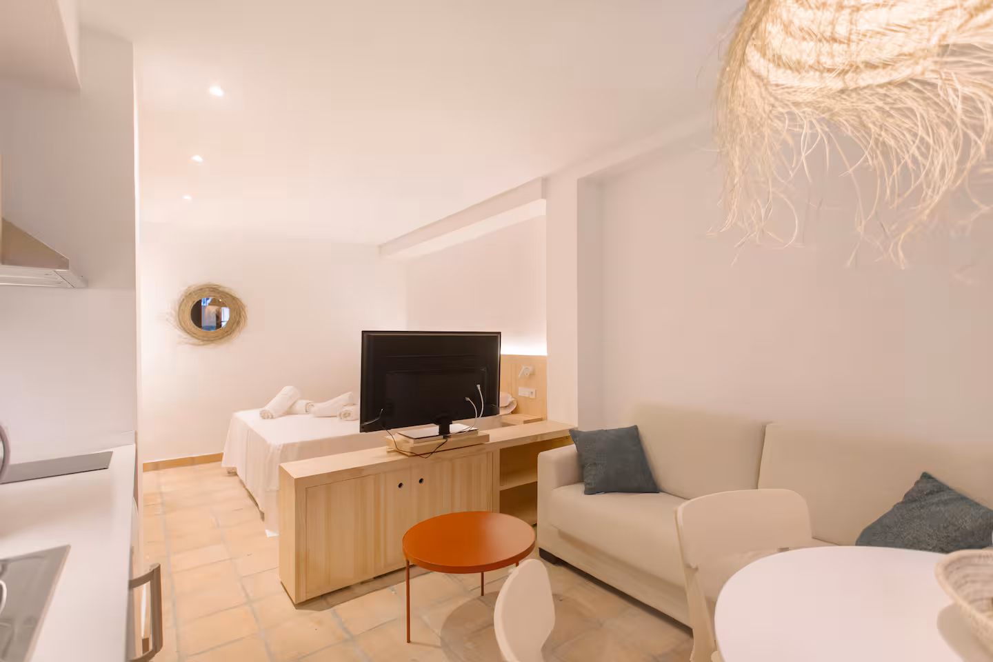 Interior de planta abierta de Artemaris con cama, sofá y lámpara de fibra trenzada