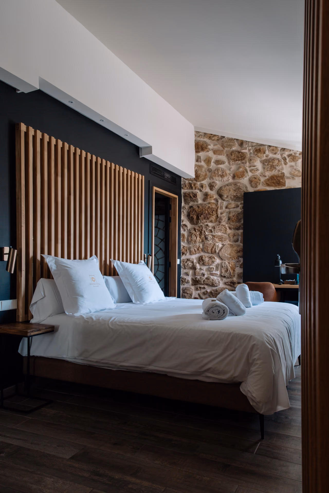 Habitación Pou con pared de piedra vista y cabecero de madera